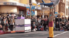 a group of people are watching a clown perform in front of a building with a sign that says hello kitty