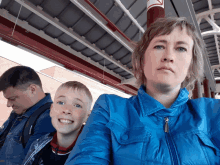 a woman wearing a blue jacket is sitting next to two children