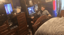 a boy sits in front of a computer screen with a sign on the wall that says ' a ' on it