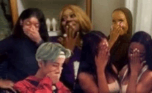 a group of women are covering their mouths with their hands while laughing .