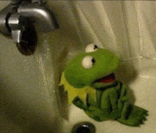 a stuffed kermit the frog is sitting in a sink