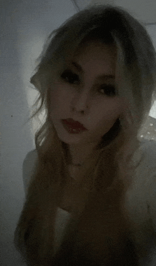 a woman with long blonde hair is taking a selfie in a dark room