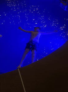 a man is floating in a pool with blue lights behind him