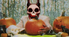 a man with a skull on his face is holding a large pumpkin