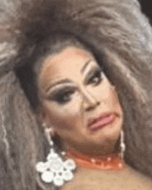 a drag queen is making a funny face while wearing a choker and earrings .