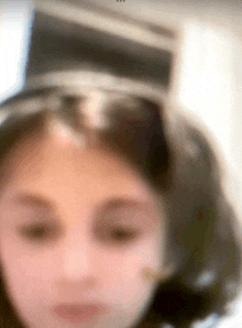 a blurry picture of a girl 's face with a hat on her head