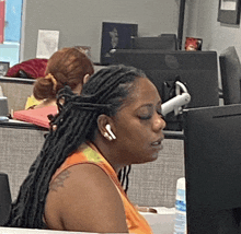 a woman with dreadlocks sits at a desk in front of a computer