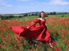 a woman in a red dress is walking through a field of red flowers