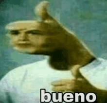 a blurry picture of a man giving a thumbs up with the word bueno written on it .