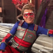 a young man in a superhero costume is sitting on a couch .