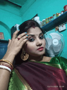 a woman standing in front of a fan with the date of 12/11/2023