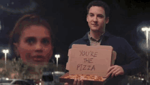 a man is holding a pizza box that says you 're the pizza .