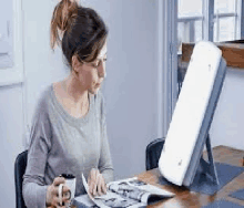 a woman is sitting at a table reading a magazine with a light therapy device .