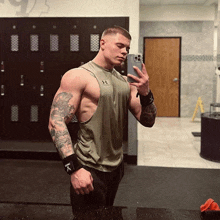 a man in an under armour tank top takes a selfie in a locker room