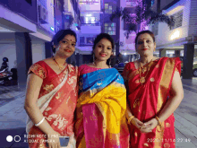 three women posing for a picture with a redmi note 7 pro in the background