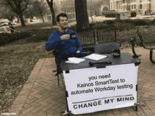 a man sits at a desk with a sign that says change my mind