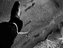 a black and white photo of a person 's foot standing on a beach next to a body of water .