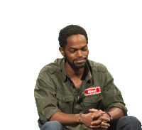 a man wearing a name tag that says hari sits with his hands folded