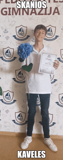 a young man is holding a flower and a certificate in front of a wall that says skanios gimnazija