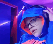 a person wearing glasses and a blue hoodie with a microphone on their head