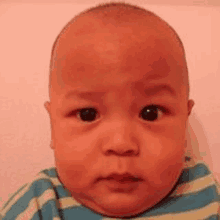 a close up of a baby 's face with a striped shirt on .