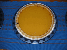 a pumpkin pie is on a blue plate on a blue table cloth