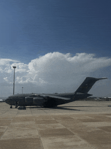 a large military plane is parked on a runway with a blue sky behind it