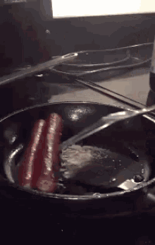 hot dogs are being cooked in a frying pan with a spatula