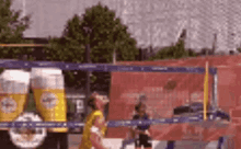 a man in a yellow shirt is playing volleyball in front of a truck with beer glasses on it .