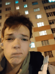 a young man making a sad face in front of a large building