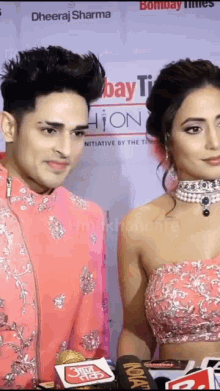 a man and a woman are standing next to each other on a red carpet in front of a sign that says bombay times