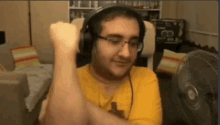 a man wearing headphones and glasses is flexing his muscles in a living room .