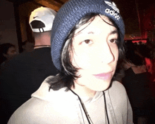 a person wearing a blue adidas beanie looks at the camera