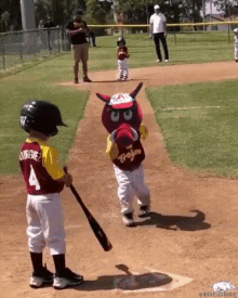 a little boy wearing a jersey with the number 4 is playing baseball with a mascot holding a bat .