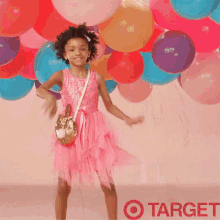 two girls in pink dresses are standing next to each other in front of balloons with target written on the bottom