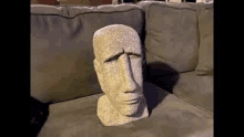 a stone statue of a head is sitting on a couch .