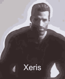 a man with a beard is standing in front of a white background with the name xeris written on it .