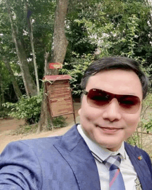 a man in a suit and tie takes a selfie in front of a sign that says ' a ' on it