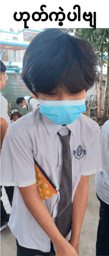 a boy wearing a face mask and a white shirt with a badge that says ' u ' on it