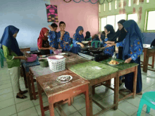 a group of people are preparing food in a classroom with a sign that says " cooking "