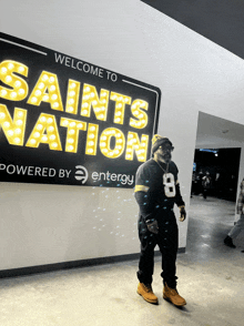 a man stands in front of a saints nation sign