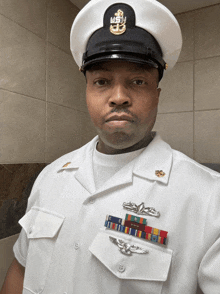 a man in a white uniform with a navy hat