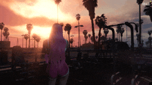 a woman with pink hair stands in front of a sunset