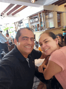 a man and a woman are posing for a picture and the man is wearing a black polo shirt