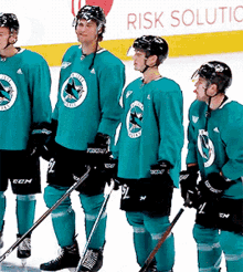 a group of ice hockey players standing on the ice with a sign that says risk solution in the background