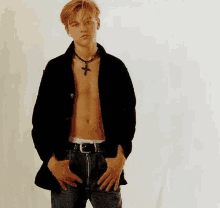 a shirtless young man wearing a black jacket and jeans