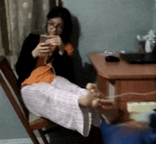 a woman is sitting in a chair with her feet up while using her phone