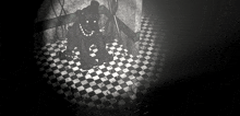 a black bear is sitting on a checkered floor in a dark room