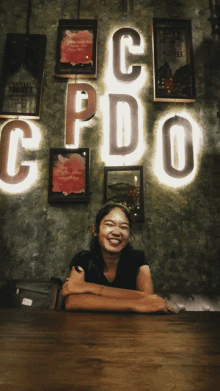 a woman sits at a table in front of a sign that says cpdo on it