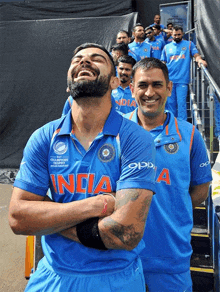 a man wearing a blue india shirt laughs